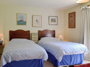 A double bed with a wooden headboard, two bedside tables, and a nightstand with a lamp.