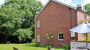 Ein Backsteinhaus mit Garten, Gartenmöbeln und einem Picknicktisch.