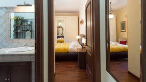 A hotel room with a wooden floor, a bed with yellow bedding, a bedside table with a lamp, a large mirror, and a bathroom with a sink and shower. - Cosy apartment for 6 guests with WIFI, A/C, TV and balcony (Rome)