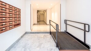 A modern hallway with a marble floor, a metal railing, and wooden storage units on the left. - Cosy apartment for 6 guests with WIFI, A/C, TV and balcony (Rome)