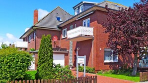 A two-story brick house with a satellite dish, a garage, and a wooden fence. - Nice apartment for 2 people with WIFI, TV and balcony (Norden)