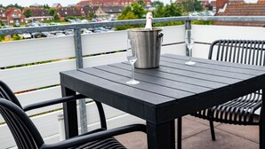 A terrace with a table and chairs, a champagne bucket, and a glass. - Nice apartment for 2 people with WIFI, TV and balcony (Norden)