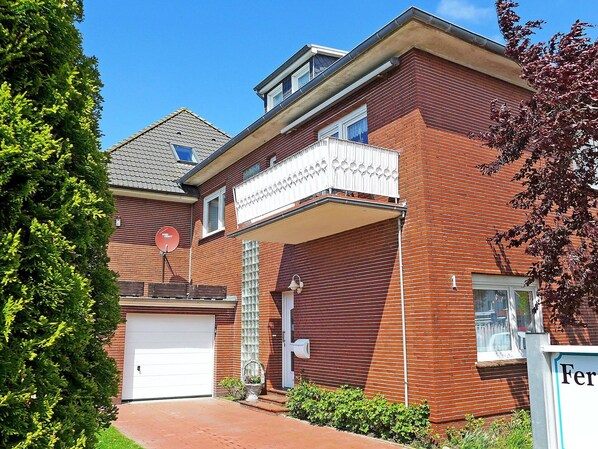 Two-story building with a balcony and garden area.