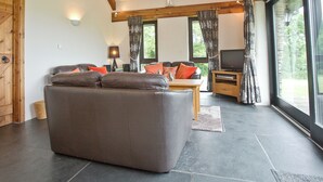 A living room with a sofa, a television, and a window with curtains. - 3 bedroom accommodation in St Issey, Wadebridge (St Issey, Wadebridge)