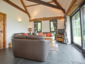 A living room with a sofa, a television, and a window with curtains. - 3 bedroom accommodation in St Issey, Wadebridge (St Issey, Wadebridge)