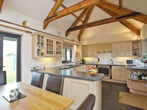 A kitchen with wooden beams, a dining area with a table and chairs, and a view of the outdoors. - 3 bedroom accommodation in St Issey, Wadebridge (St Issey, Wadebridge)