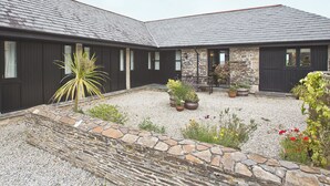 A building with a stone facade, multiple windows, and a gravel courtyard with potted plants. - 3 bedroom accommodation in St Issey, Wadebridge (St Issey, Wadebridge)