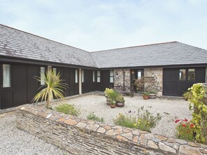 A building with a stone facade, multiple windows, and a gravel courtyard with potted plants. - 3 bedroom accommodation in St Issey, Wadebridge (St Issey, Wadebridge)