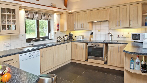 A modern kitchen with wooden cabinets, a built-in oven, a microwave, and a sink. - 3 bedroom accommodation in St Issey, Wadebridge (St Issey, Wadebridge)
