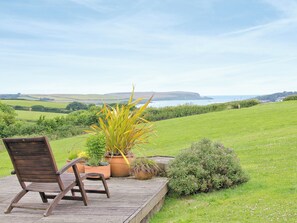 A wooden deck with a chair and potted plants overlooking a green landscape and distant hills. - 3 bedroom accommodation in St Issey, Wadebridge (St Issey, Wadebridge)