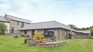A stone house with a patio, outdoor seating, and a grassy yard. - 3 bedroom accommodation in St Issey, Wadebridge (St Issey, Wadebridge)