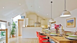 Een ruime keuken met houten vloeren, een eethoek met een houten tafel en een rode stoel.