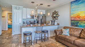 A modern kitchen with white cabinets, stainless steel appliances, and a bar area with stools.