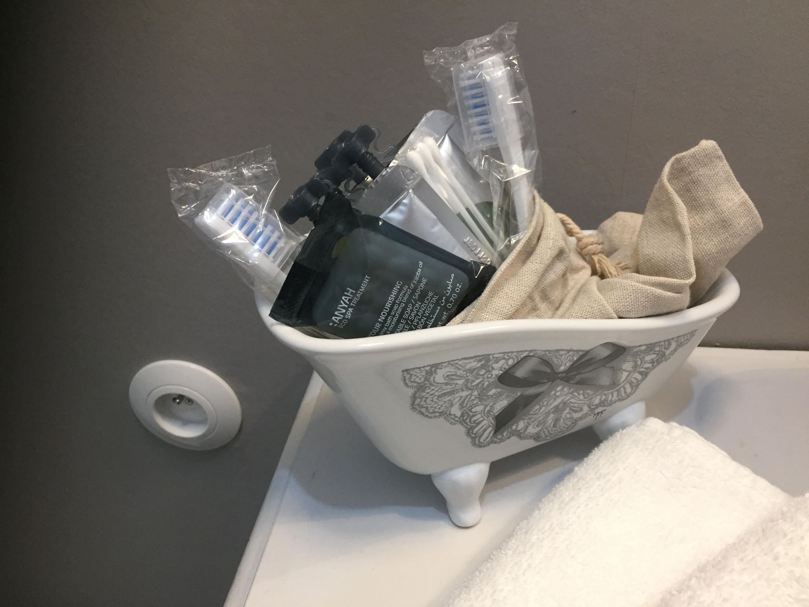 Un lavabo de baño con una pila decorativa que contiene artículos de aseo.