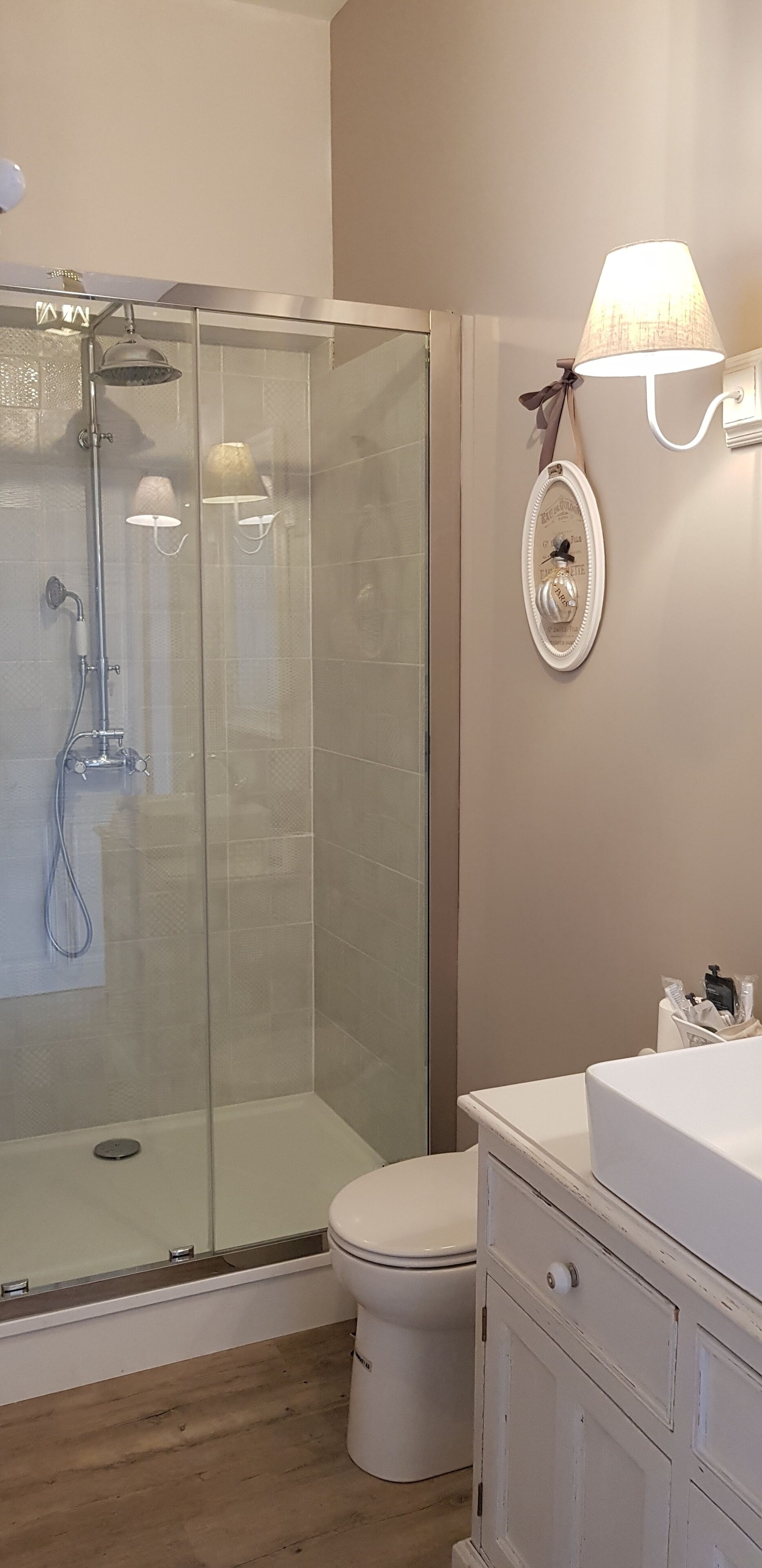 Un baño con ducha envuelta en vidrio, inodoro y tocador con lavamanos.