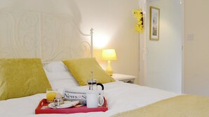 A neatly made bed with white and yellow pillows, a tray with breakfast items, and a bedside lamp. - 2 bedroom accommodation in Keswick (Keswick)