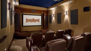 Ett hemmabiorum med ett stjärnhimmelmålat tak, en storbildsskärm som visar "Grand Lodge" och flera bekväma läderfåtöljer.