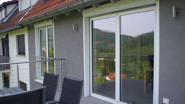 A balcony with a glass door and a view of a forested hillside. - New vacation apartment in Neckargemünd near Heidelberg (Neckargemünd)