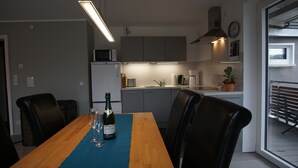A modern kitchen with grey cabinets, a microwave, and a coffee machine. There is a dining table with chairs and a bottle of champagne. - New vacation apartment in Neckargemünd near Heidelberg (Neckargemünd)