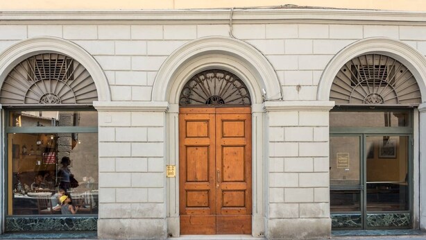 Un edificio con una puerta central de madera flanqueada por dos ventanas arqueadas con rejas decorativas.