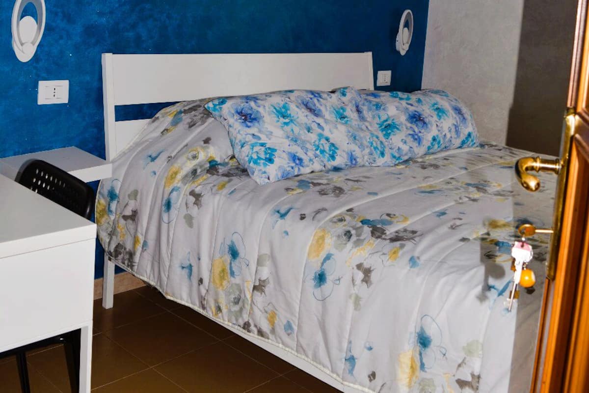 Un dormitorio con cama, escritorio y un cuadro colgado en la pared.
