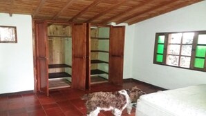Ett rum med ett träpanelat tak, en säng, ett fönster med grönfärgat glas och en hund.