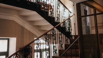 Una escalera con barandillas de metal negro ornamentado y escalones de madera.