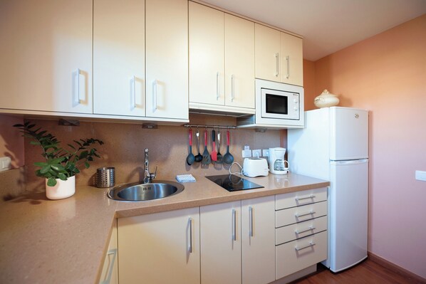 A kitchen with white cabinets, a stainless steel sink, a microwave, and a refrigerator. - Luxury Villa in an idyllic setting, in Santa Brígida, Gran Canaria. (Santa Brigida)