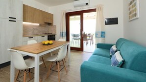 Eine moderne Küche mit weißen Schränken, einem Holztisch und einem blaugrünen Sofa.