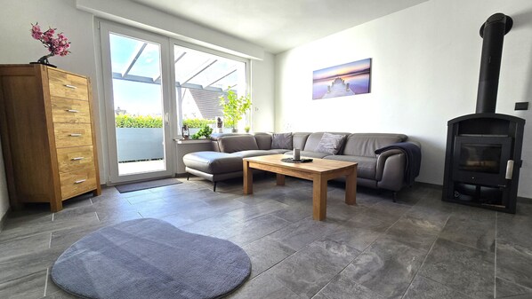 A living room with a sofa, a wooden cabinet, a fireplace, and a view through a sliding door.