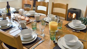 A dining table set with white plates, bowls, glasses, and cutlery, with a bottle and candle on the table. - 4 bedroom accommodation in Nantglyn, near Denbigh (Nantglyn, near Denbigh)