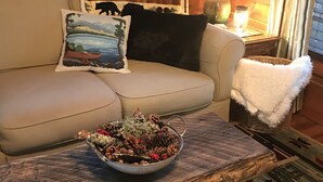Een gezellige woonkamer met een bank, een salontafel met een decoratieve schaal, een lamp en een raam met gordijnen.