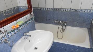 Un baño con lavamanos blanco, una bañera y un espejo.