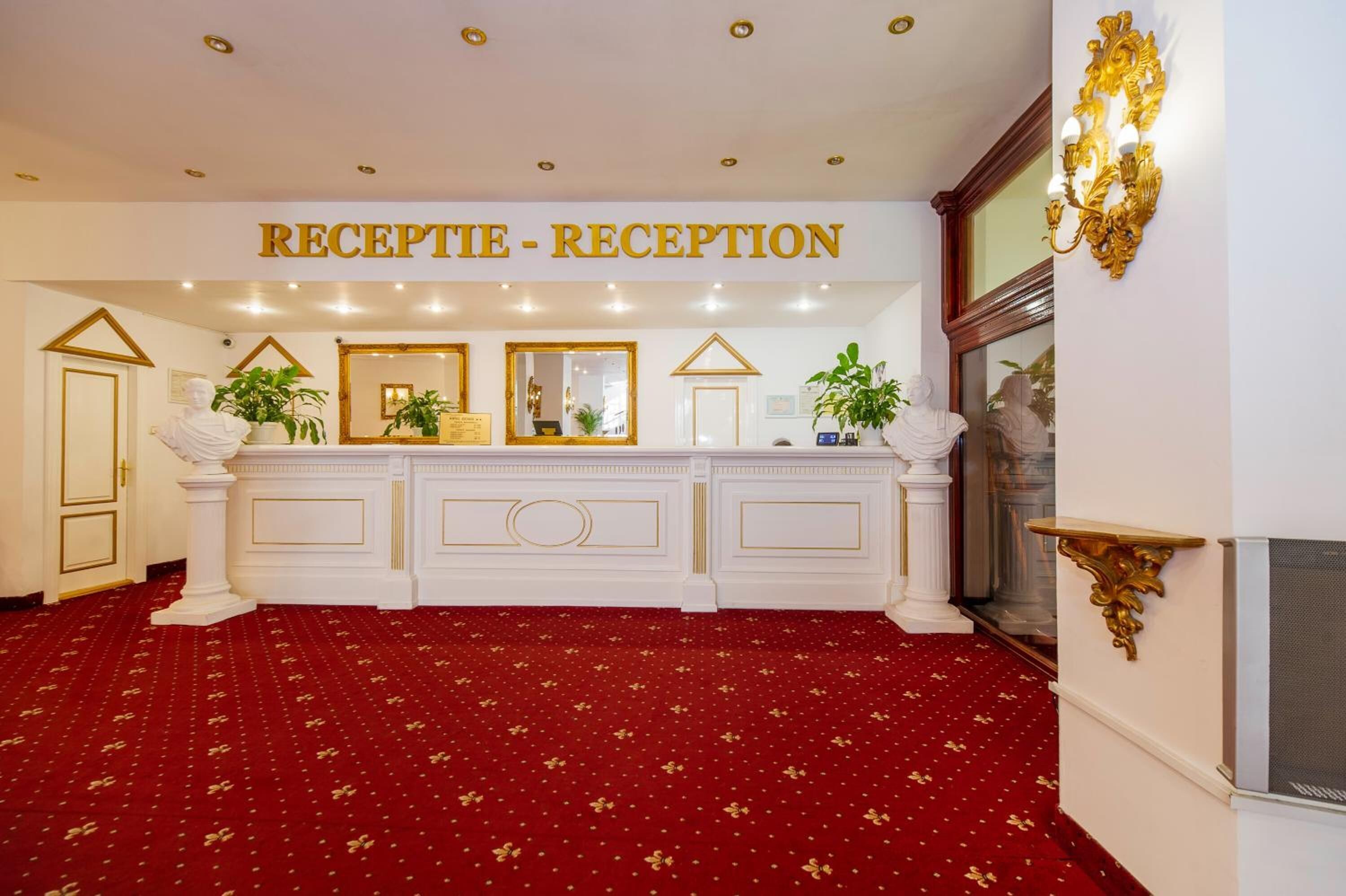 Un área de recepción con alfombra roja, un mostrador blanco y un letrero que dice "RECEPTION - RECEPTION".