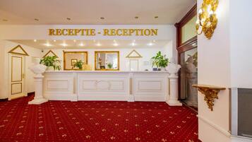 Un área de recepción con alfombra roja, un mostrador blanco y un letrero que dice "RECEPTION - RECEPTION".
