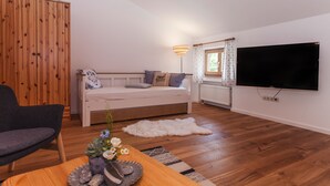 A cozy room with a sofa, a chair, a TV, and a wooden wardrobe. - Schönes Ammertal (Oberammergau)