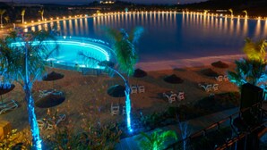 A nighttime view of a resort with a pool, palm trees, and a beach area. - Exclusive 3-bed Penthouse Alcazaba Lagoon (321) (Casares)