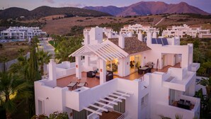 A modern white villa with a patio, surrounded by hills and mountains. - Exclusive 3-bed Penthouse Alcazaba Lagoon (321) (Casares)
