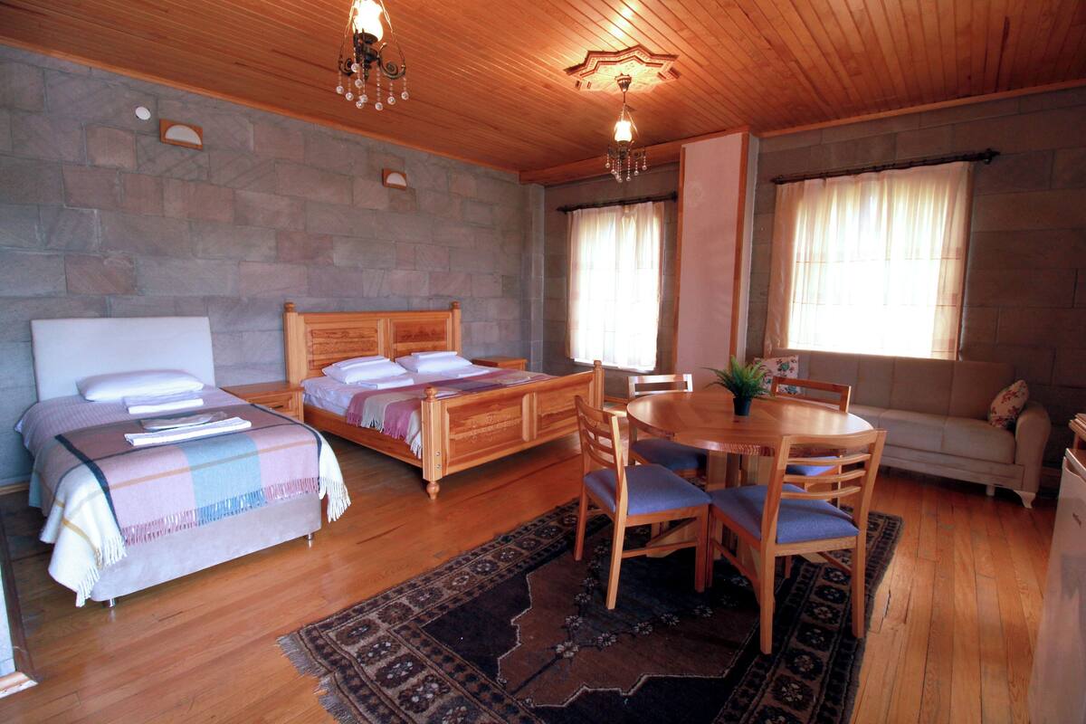A cozy room with a bed, a dining table with chairs, and a small seating area.