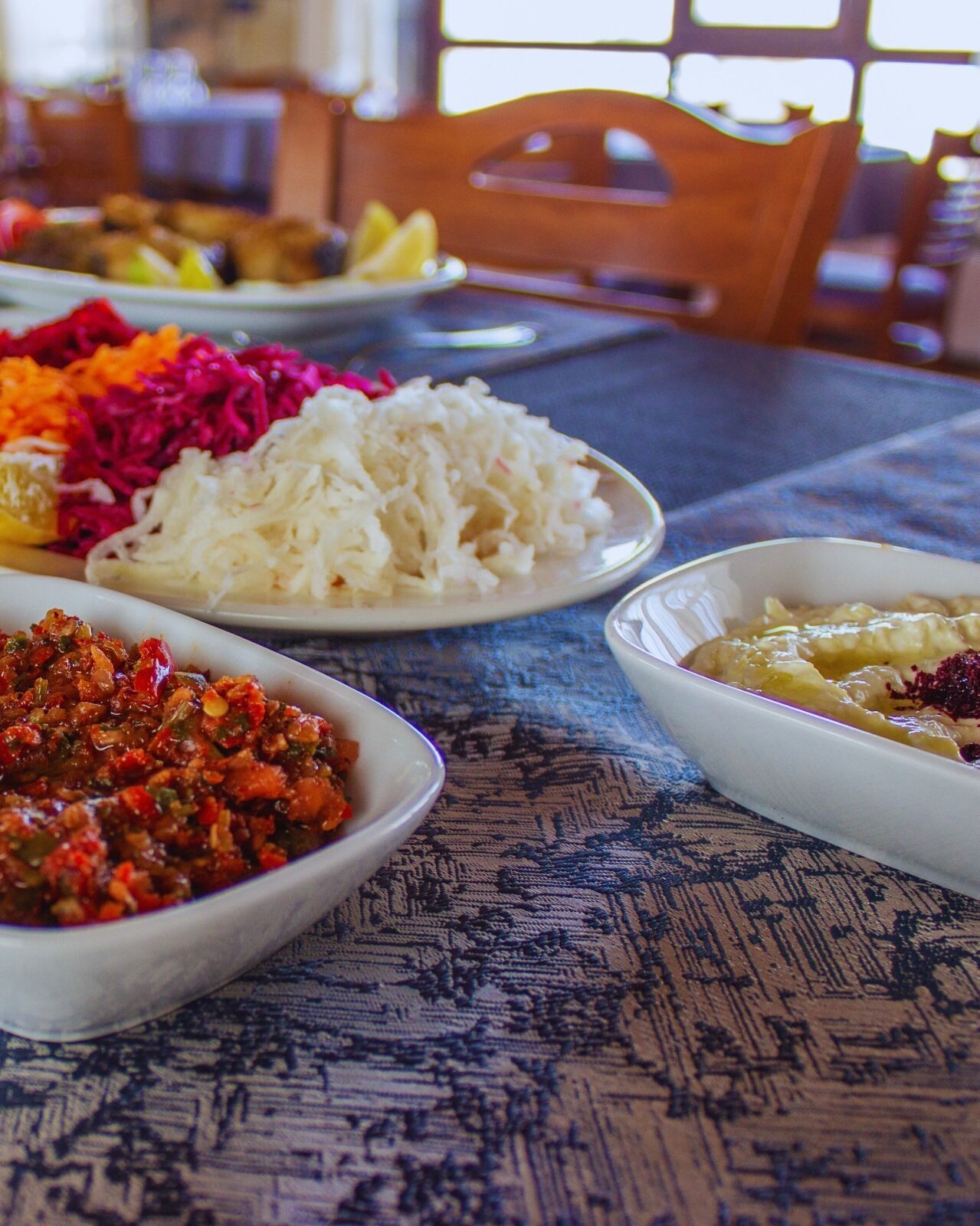 A dining table with various dishes, including a bowl of red sauce, white rice, and a dish with vegetables.