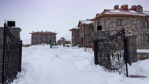 Un sendero cubierto de nieve que conduce a un edificio de piedra con una reja de metal.