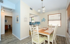 A dining area with a wooden table, white chairs, and a blue backsplash.