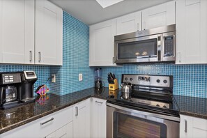 A modern kitchen with white cabinets, a stainless steel microwave, a stove, and a coffee maker. - Steps from the beach 2BR @Manatee Beach (Holmes Beach)
