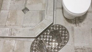 Un baño con ducha, inodoro y un tapete de piso estampado.