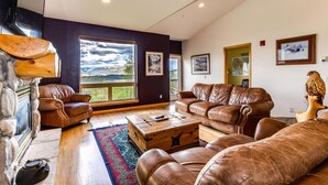 A spacious living room with leather sofas, a wooden coffee table, and a large window offering a scenic view. - Exceptional Views, Large Townhome, Hot Tub, Pool, Private Garage 97A (Silverthorne)