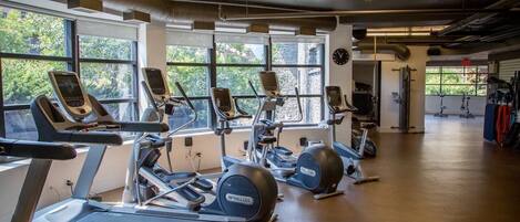 Un gimnasio con cintas de correr, elípticas y bicicletas estáticas.