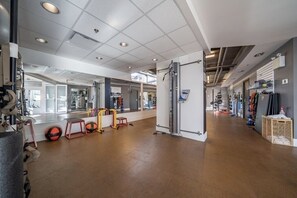 A gym with exercise equipment, a mirror, and a large window.