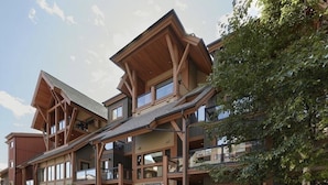 Een meerlaags houten lodge met grote ramen en een balkon.