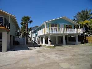 A two-story house with a balcony, surrounded by palm trees. - Location! Steps from Manatee Beach 2BR (Holmes Beach)