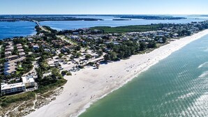 Ein Luftbild einer Küstenstadt mit einem langen Sandstrand, einem dicht bebauten Wohngebiet und einer Marina.